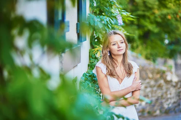 Hermosa joven en vestido blanco apoyada contra la pared en Montmartre —  Fotos de Stock