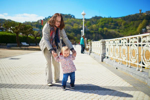 Grandmother helping granddaughter make her firts steps — Stock Photo, Image