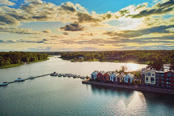 Aerial view of colorful boats near wooden berth and buildings in the countryside of Finland at sunset — Stock Photo, Image
