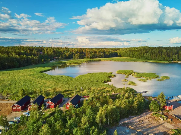 Vista aérea de barcos de colores cerca de amarradero de madera y edificios en el campo de Finlandia al atardecer —  Fotos de Stock