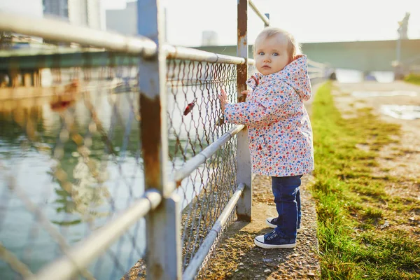 Niña de un año parada junto a valla metálica en el parque — Foto de Stock