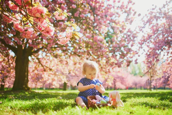 Süßes einjähriges Mädchen sitzt auf dem Gras und isst Erdbeeren — Stockfoto