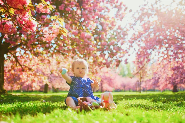 Süßes einjähriges Mädchen sitzt auf dem Gras und isst Erdbeeren — Stockfoto