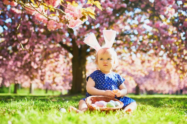 Bonito menina de um ano sentada na grama e comer morangos — Fotografia de Stock