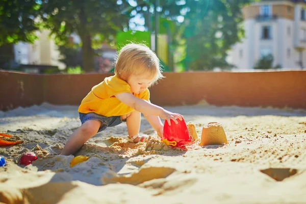 Маленькая девочка развлекается на детской площадке в песочнице — стоковое фото