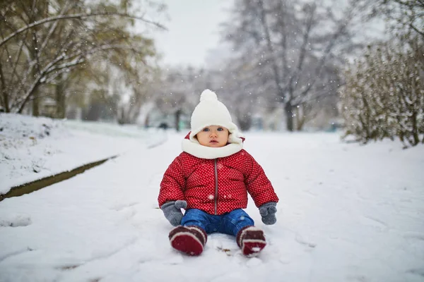 Szczęśliwy uśmiechnięta dziewczynka siedzi na śniegu — Zdjęcie stockowe
