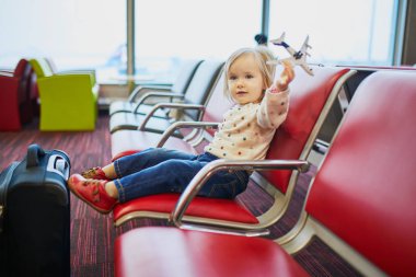 Çocuk kapıda oturuyor ve uçuşu bekliyor.