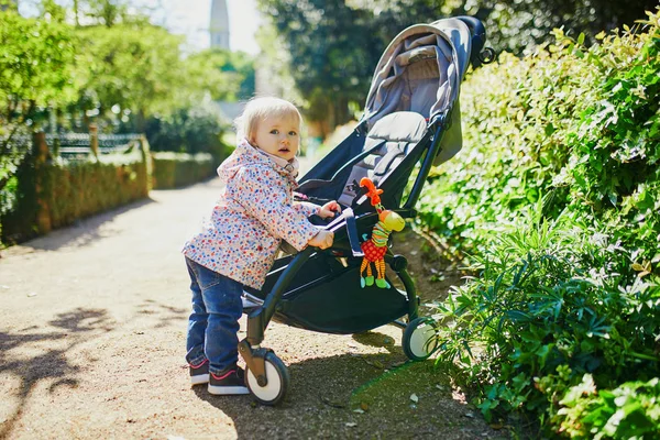 Maluch dziewczyna stoi obok jej wózek w parku — Zdjęcie stockowe