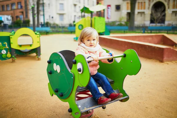 Чарівна дівчинка-малюк розважається на весняному гонщику на дитячому майданчику — стокове фото