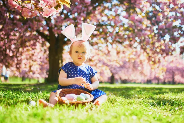 Słodkie jeden rok stary dziewczyna siedzi na trawie i jedzenie truskawek — Zdjęcie stockowe