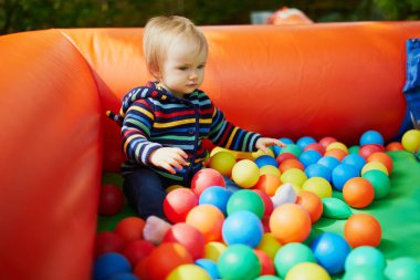 Küçük kız top havuzunda oynuyor. Toddler topları ile eğleniyor. Çocuklar için renkli oyuncaklar.