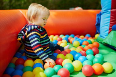 Küçük kız top havuzunda oynuyor. Toddler topları ile eğleniyor. Çocuklar için renkli oyuncaklar.