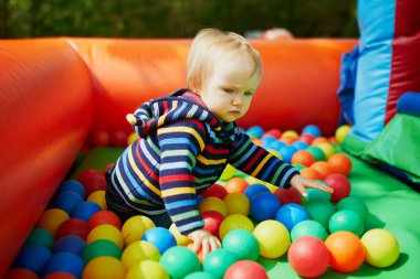 Küçük kız top havuzunda oynuyor. Toddler topları ile eğleniyor. Çocuklar için renkli oyuncaklar.