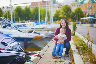 Bir yaşındaki çocuğuyla birlikte setin orada mutlu bir genç kadın. Anne ve kızı Helsinki caddesinde. Finlandiya 'da tatil sırasında iki kişilik bir aile. Çocuklarla seyahat etmek.