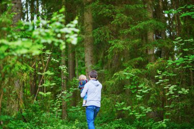 Baba ormanda yürürken çocuğunu taşıyor. Küçük kızıyla birlikte doğanın tadını çıkaran bir adam.