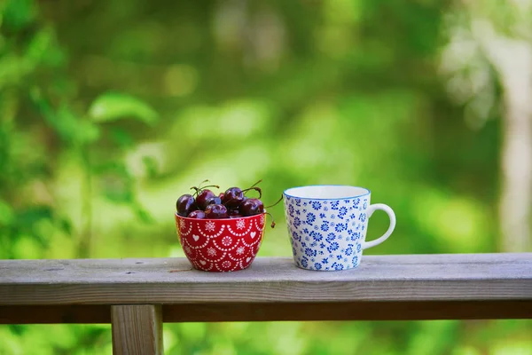 黒コーヒーと甘いチェリーのボウルのカップ — ストック写真