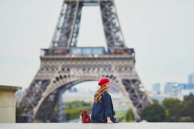 Paris, Fransa 'da uzun sarı kıvırcık saçlı genç bir kadın. Eyfel Kulesi 'nin yanındaki kırmızı bereli güzel turist.