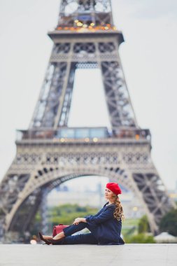 Paris, Fransa 'da uzun sarı kıvırcık saçlı genç bir kadın. Eyfel Kulesi 'nin yanındaki kırmızı bereli güzel turist.