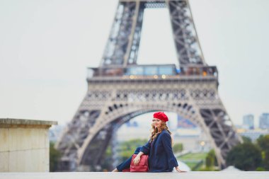 Paris, Fransa 'da uzun sarı kıvırcık saçlı genç bir kadın. Eyfel Kulesi 'nin yanındaki kırmızı bereli güzel turist.