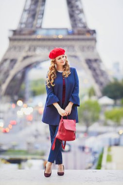 Paris, Fransa 'da uzun sarı kıvırcık saçlı genç bir kadın. Eyfel Kulesi 'nin yanındaki kırmızı bereli güzel turist.
