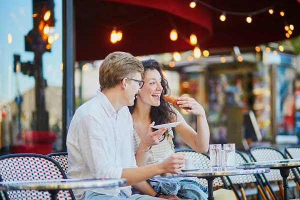 Happy romantic couple in Paris, drinking coffee in traditional Parisian outdoor cafe. Tourists spending their vacation in France