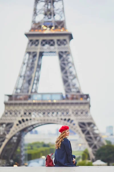 一个有着一头长长的金黄色卷发的年轻女子 艾菲尔铁塔附近身穿红色贝雷帽的漂亮游客 — 图库照片