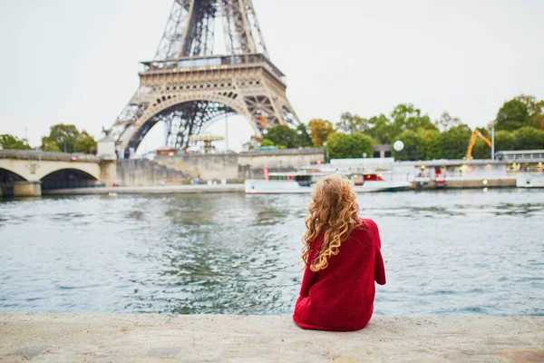 一个有着一头长长的金黄色卷发的年轻女子 塞纳河堤埃菲尔铁塔附近穿着红色外套的漂亮游客 — 图库照片