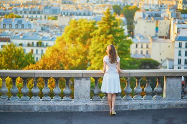 Güzel genç bir kadın Paris, Fransa manzarasının tadını çıkarıyor. Montmartre tepesinde beyaz elbiseli bir kız.
