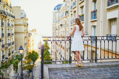 Beyaz elbiseli güzel bir kadın sabahın erken saatlerinde Fransa 'nın Paris şehrinde Montmartre tepesinde yürüyor.
