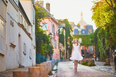 Beyaz elbiseli güzel bir kadın sabahın erken saatlerinde Fransa 'nın Paris şehrinde Montmartre tepesinde yürüyor.