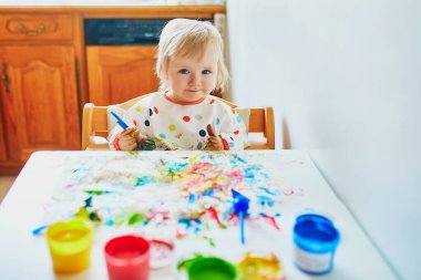Anaokulunda ya da anaokulunda parmaklarıyla resim yapan sevimli küçük bir kız. Evde kalan çocuklar için yaratıcı oyunlar