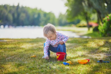 Toddler kum kalıpları, kova ve kürek ile oynarken, mudpies yapma ve küçük taşlar toplama. Çocuklar için açık yaratıcı etkinlikler