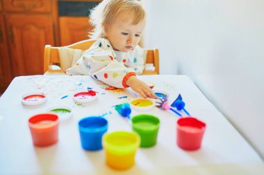 Anaokulunda ya da anaokulunda parmaklarıyla resim yapan sevimli küçük bir kız. Evde kalan çocuklar için yaratıcı oyunlar