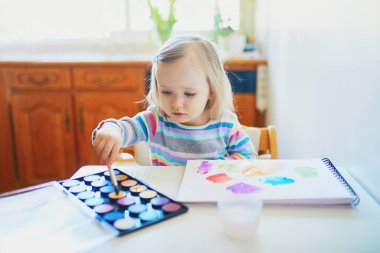Anaokulunda ya da anaokulunda Aquarelle 'le resim yapan sevimli küçük bir kız. Evde kalan çocuklar için yaratıcı oyunlar