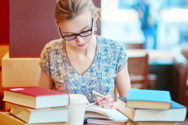 Kitapları ve kağıtları olan bir öğrenci, evde çalışıyor. Koronavirüs salgını sırasında karantina ve kapalı okullar ve ofisler. Evde eğitim, uzak öğrenim ve serbest meslek