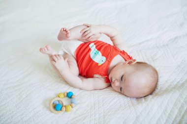 Yatakta sırtüstü yatan tatlı bir kız bebek. Bebek odasında oyuncağı olan sağlıklı, mutlu bir çocuk.