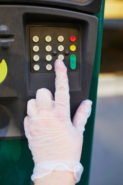 Fransa 'nın Paris şehrinde bir caddede tek başına koruma sağlayan bir kadın parkmetre tuşu kullanıyor. Salgın ve salgın sırasında karantina ve kendini izole etme