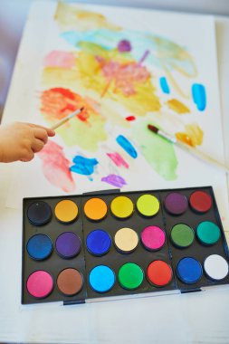 Renkli akvaryumlu resim çizen kız evde, anaokulunda ya da anaokulunda, palete yakın çekim yapıyor. Çocuklar için yaratıcı oyunlar, eğitim ve uzak mesafe eğitimi. Evde kalıp eğlenin.