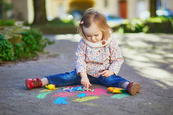 可爱的蹒跚学步的小女孩用彩色粉笔画沥青 幼儿户外活动及创意游戏 — 图库照片