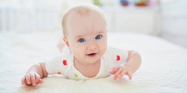 Yatakta göbeğinde yatan tatlı bir kız çocuğu. Kreşteki sağlıklı çocuk.
