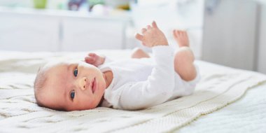 Sevimli bir kız bebek bebek odasında yatakta yatıyor.