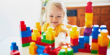 Anaokulunda ya da anaokulunda renkli plastik bloklarla oynayan sevimli küçük bir kız. Çocuklar için yaratıcı oyunlar