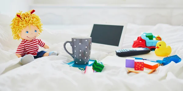 ノートパソコン コーヒー ノートブック ベッドの中で別のおもちゃのカップをきれいに白いリネン フリーランス 遠隔教育 または子供の概念を持つ家庭からの仕事 — ストック写真