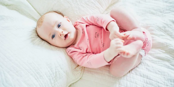 Het Kleine Meisje Ligt Bed Haar Rug Raakt Haar Tenen — Stockfoto