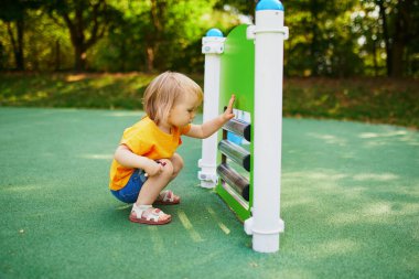Sevimli küçük kız oyun alanında eğleniyor. Çocuklar için açık hava aktiviteleri