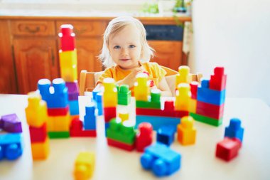 Anaokulunda ya da anaokulunda renkli plastik bloklarla oynayan sevimli küçük bir kız. Yaratıcı oyunlar ve çocuklar için ev eğlencesi