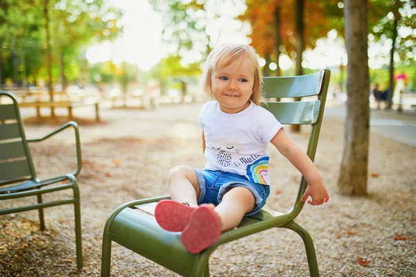 幸せな女の子はパリ フランスのルクセンブルクの庭の緑の金属椅子に座っている — ストック写真