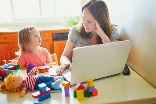 疲れ果て ストレスの多い母親は幼児と一緒に家から働いています コロナウイルス発生時の隔離および閉鎖保育所 仕事中の子供は騒音や不穏な女性を作ります 子供とのフリーランスの仕事 — ストック写真