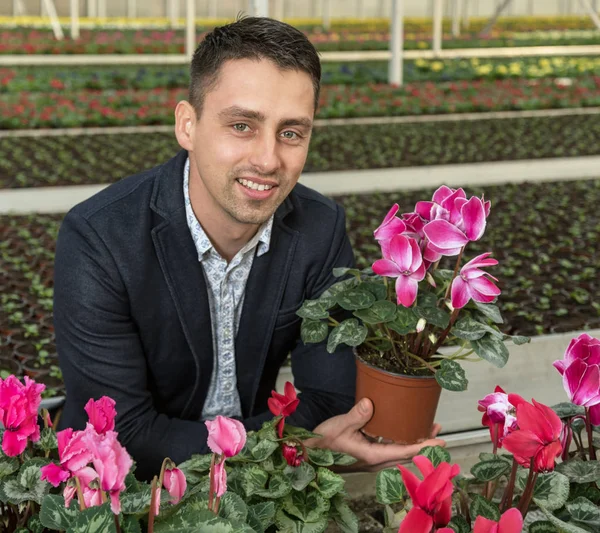 Smiling young man in greenhouse.