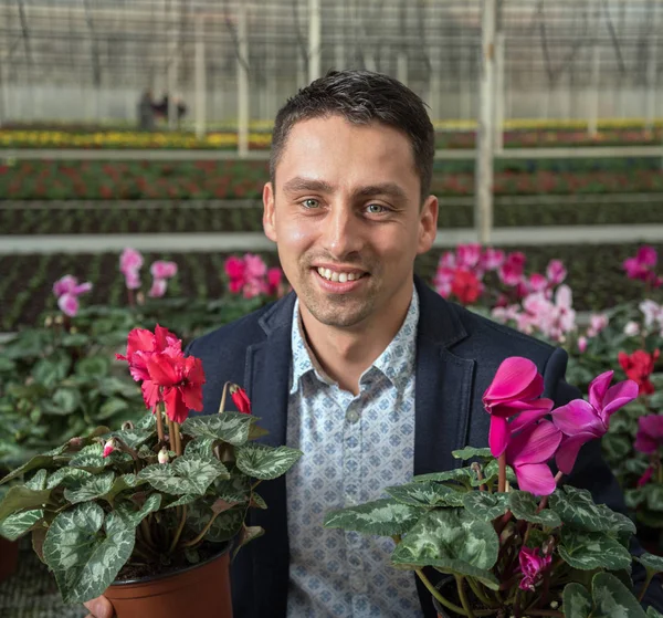 Smiling young man in greenhouse.